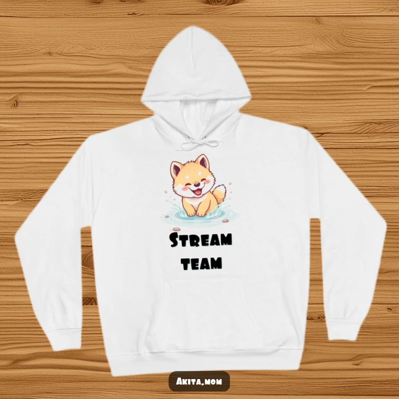 Funny Akita cub hoodie depicting a giggling puppy splashing playfully in a clear stream, ideal for cozying up after fun.